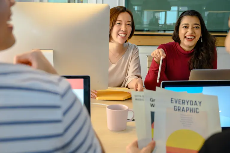 Two smiling women in a group meeting