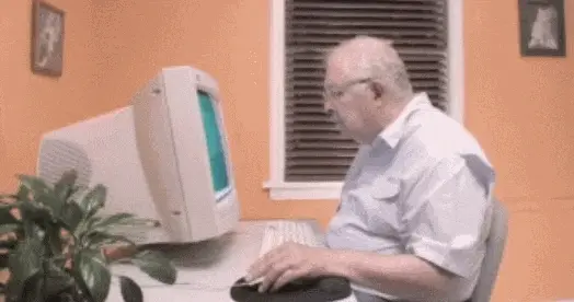 A man at a computer desk appearing frustrated with technology