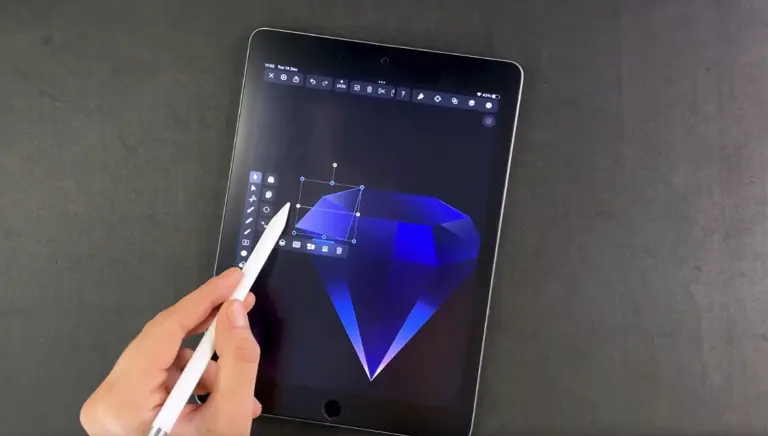 Hand with stylus editing a facet of a blue diamond graphic on a tablet