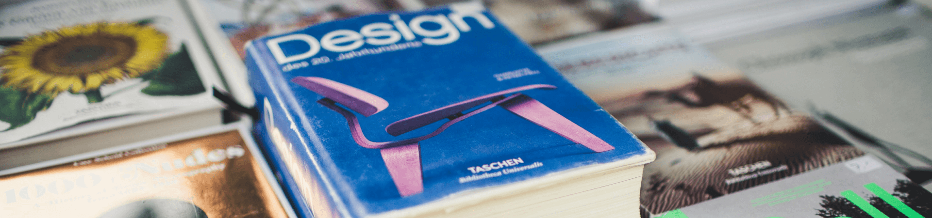 A book titled 'Design' by TASCHEN, with blurred books in the background
