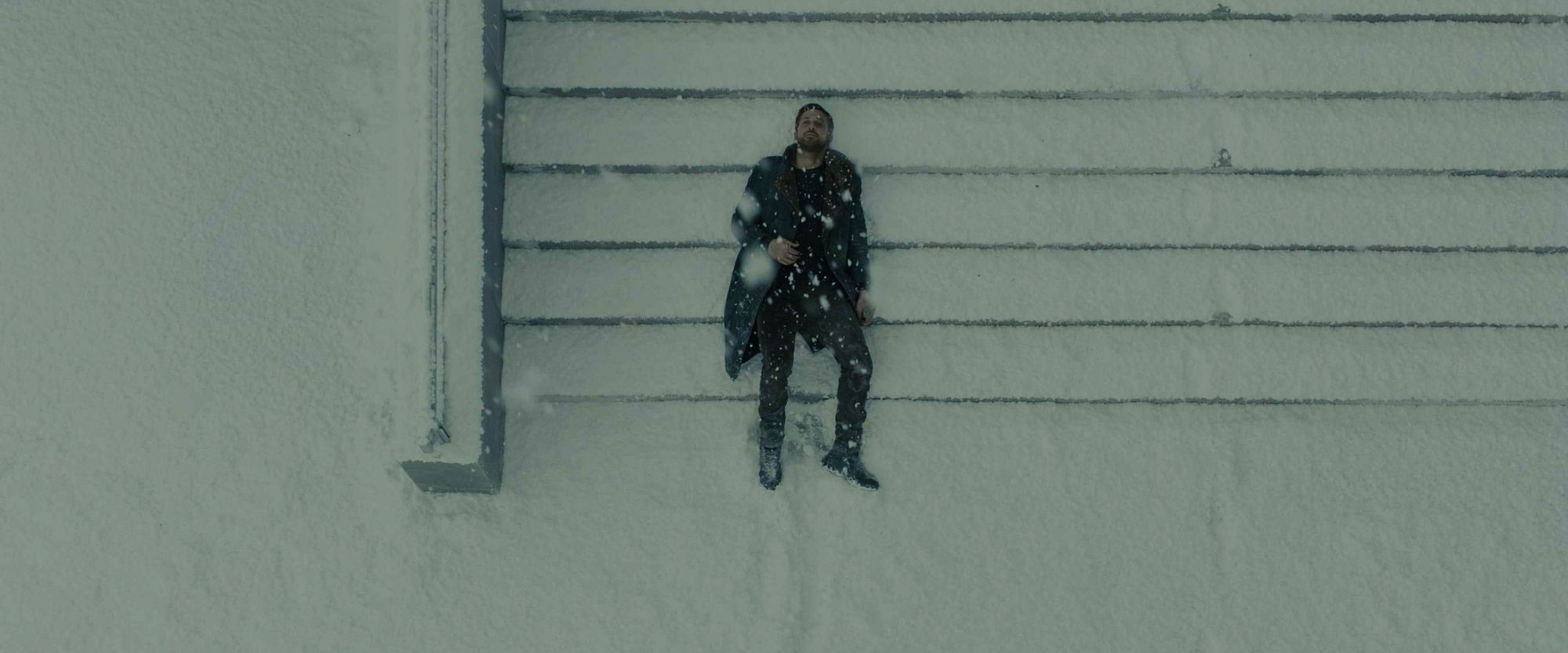 Man covered in snow lying on stairs