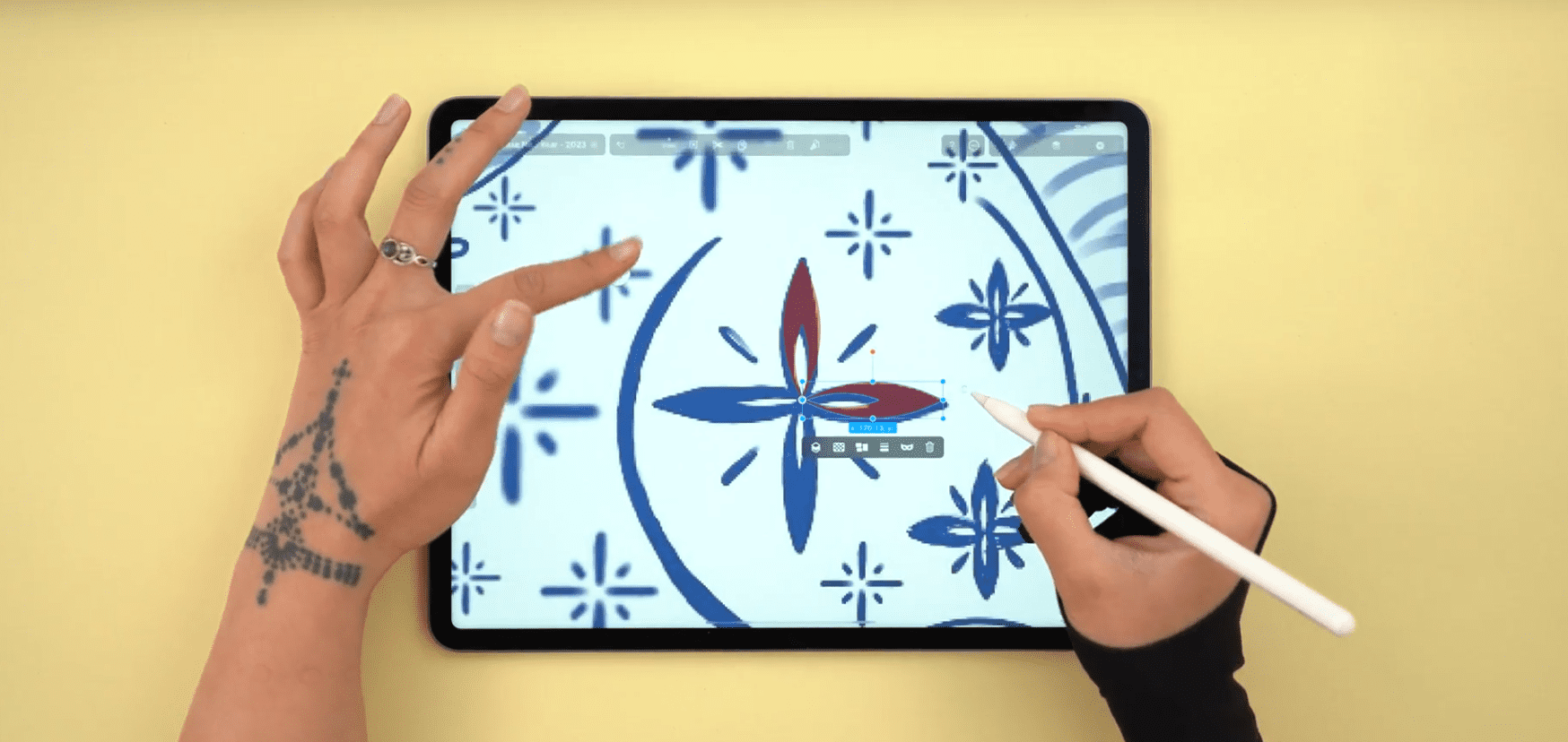  Hands using a stylus on a tablet to create a blue floral design