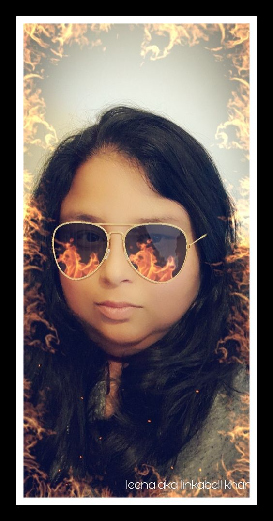 Person with flame-reflective sunglasses and fiery background.